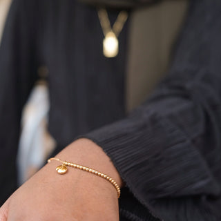 Model wearing Arabic gold bracelet with 'my sister' engraved