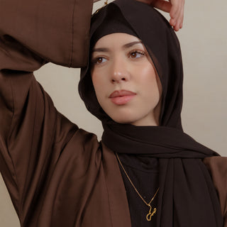 Nimah gold plated necklace worn by woman wearing a black hijab and brown abaya 