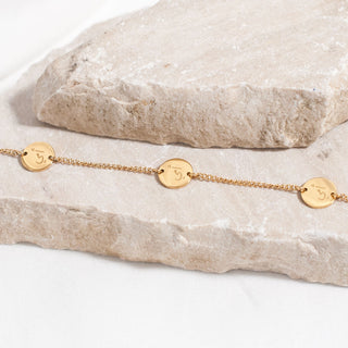 Close up of gold Arabic bracelet engraved with the word 'Mother' 